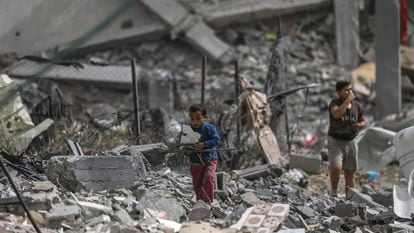 Palestinian children walk through the rubble of a building bombed by the Israeli army in Al Nuseirat camp in southern Gaza, on April 18, 2024.