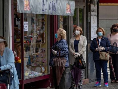 Women wearing masks wait in line to enter a store in Seville on Tuesday.