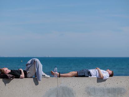 Two men resting in the sun on Malvarrosa beach in Valencia, Spain.