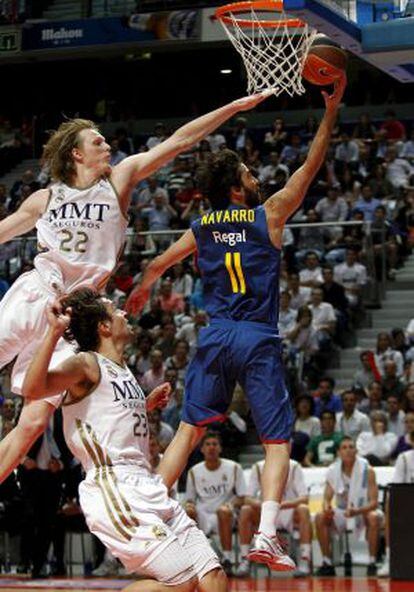 Real Madrid&acute;s Kyle Singler (l) and Sergio Llull (c) try to prevent Barcelona&#039;s Juan Carlos Navarro from scoring.