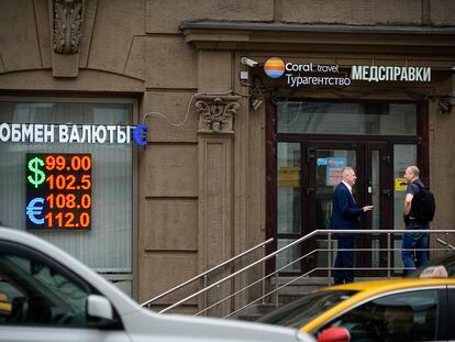 Two men talk to each other at the entrance of a currency exchange office in Moscow, Russia, Monday, Aug. 14, 2023