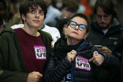 Two ERC supporters in Barcelona wear stickers against the far-right party Vox.