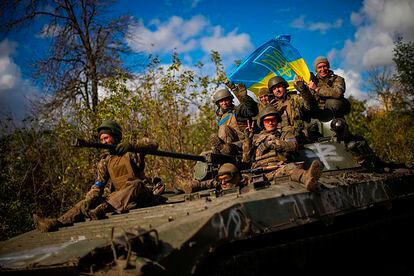Ukrainian soldiers fly the national flag as they travel in an armored vehicle from Izium to Lyman.