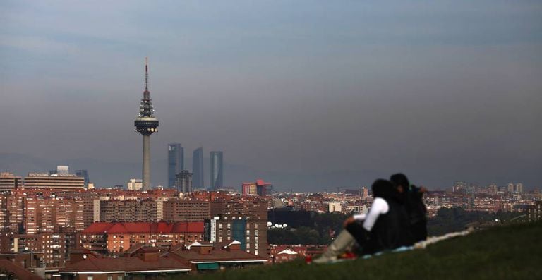 A couple look out at a smog-stained Madrid skyline.