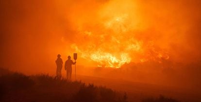 Two firefighters work to put out the blaze between Navalacruz and Riofrío on Monday.