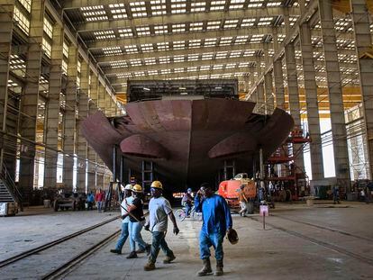 Workers pass the stern of the unfinished 260-foot-long Eco Edison ship in Terrebonne Parish, Louisiana, along the Houma Navigation Canal, on April 3, 2023.