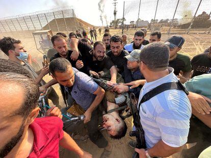 A group of Palestinians carry the body of a young Israeli who was killed on the southern border between Israel and Gaza.