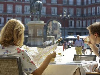 Two visitors to Madrid enjoy a drink in the sunshine of Plaza Mayor - but is anyone relaxing with a coffee?