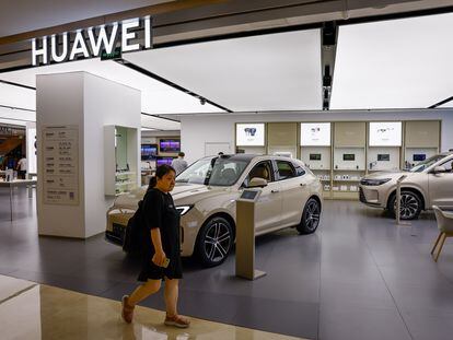 A woman walks next to a Huawei AITO M5 SUV at a showroom in Beijing, China, 10 August 2023 (issued 11 August 2023).