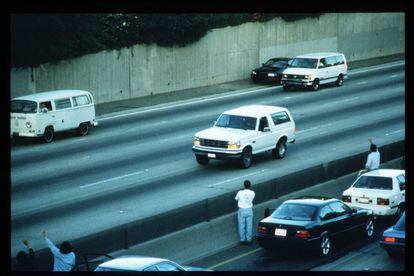 Motorists wave to ex-football star O.J. Simpson as he flees from the police in the back of a white Ford Bronco pickup truck driven by Al Cowlings in Los Angeles, California, in June 1994. 