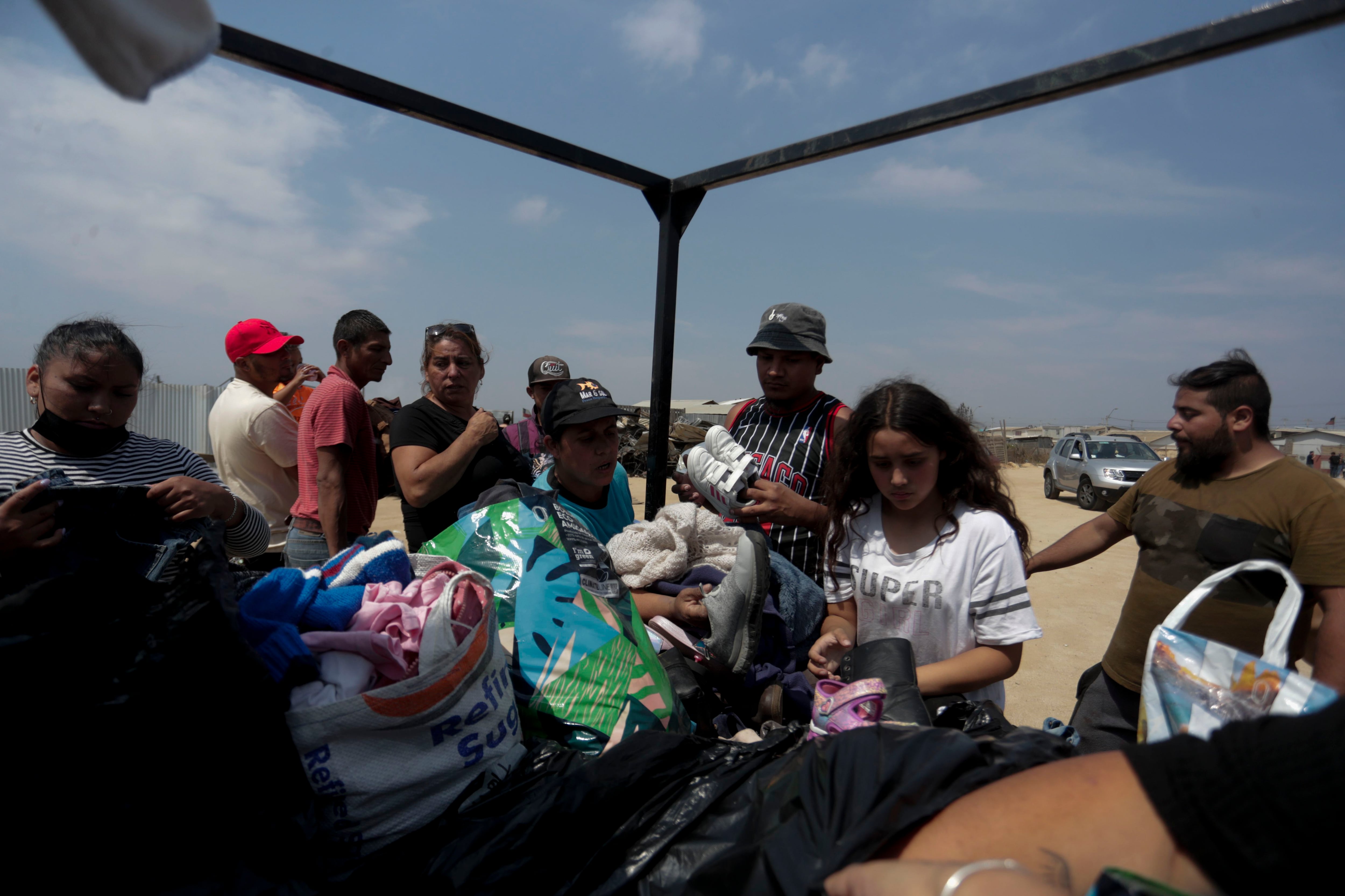 People receive clothing and water from volunteers at a makeshift camp in Viña del Mar.