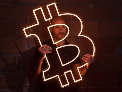 Podcaster Pau Ninja poses with a neon Bitcoin symbol.