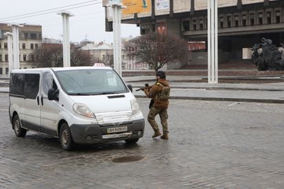 A Ukrainian law enforcement officer holds a weapon while approaching a vehicle in a street in Kharkiv.