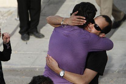 A friend hugs the deaf-mute son (in black) of one of the quake victims at Lorca's morgue.