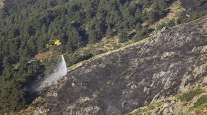 A helicopter drops water on the fire in La Morcuera.
