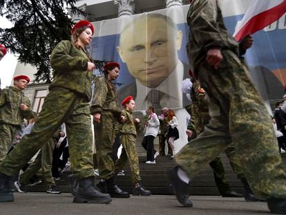 Youth take part in an action to mark the ninth anniversary of the Crimea annexation from Ukraine next to an image of Russian President Vladimir Putin in Yalta, Crimea, on March 17, 2023.