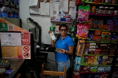 A store worker handles bolívars and dollars during a sale in Caracas, Venezuela.