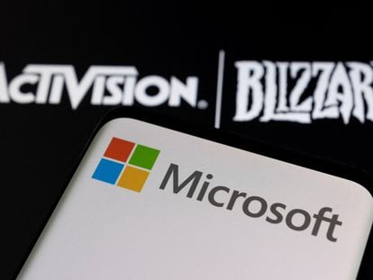 Microsoft logo is seen on a smartphone placed on displayed Activision Blizzard logo