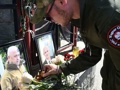 A member of the Wagner private mercenary group pays homage to Prigozhin (pictured in the photo on the left) and Utkin, outside a Wagner office in the city of Novosibirsk, on Aug. 24, 2023 .