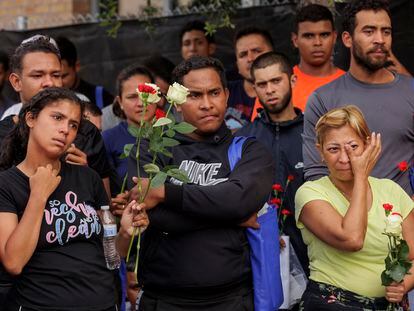 Migrants hold flowers and listen to speakers during a vigil for the eight migrants that were killed while waiting at a bus stop, in Brownsville, Texas, on May 8, 2023.