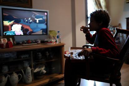 A youngster eats a slice of pizza in his home in Madrid.