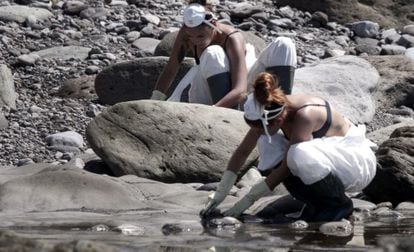Two volunteers clean up fuel at a cove in Mogán, Gran Canaria.