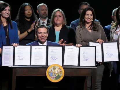 Florida Gov. Ron DeSantis holds up bills he signed during a bill signing ceremony at the Coastal Community Church at Lighthouse Point