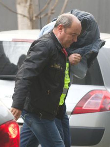 One of the arrested brothers, his head hidden beneath his jacket, arrives at court.