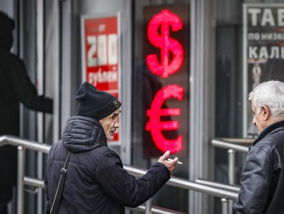Russian men speak to each other in front of a panel displaying the Euro and Dollar signs at an exchange office in Moscow, Russia, 09 February 2023.