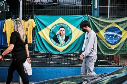 Along a boulevard in Brasilia, a woman and a child walk beneath a Brazilian flag displaying Bolsonaro’s face, September 20, 2022.