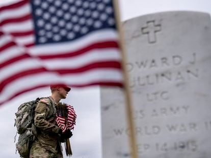 A member of the 3rd U.S. Infantry Regiment places flags in front of each headstone at Arlington National Cemetery in Arlington, on May 25, 2023,  ahead of Memorial Day.