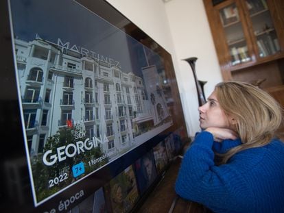A young woman sits in front of a very large television in her home in Madrid.