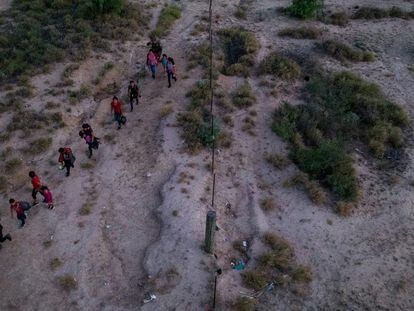 Asylum seeking migrants are escorted to a staging area by a border patrol agent after they crossed the Rio Grande into the United States, on June 13, 2022.