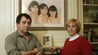 Eva Blanco's parents stand in front of a portrait of their three daughters.