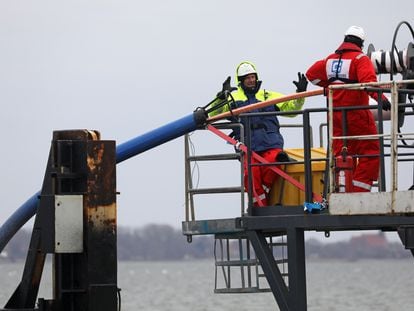 Two workers lay out a fiber optic cable between the German islands of Rügen and Hiddensee, in February 2022.