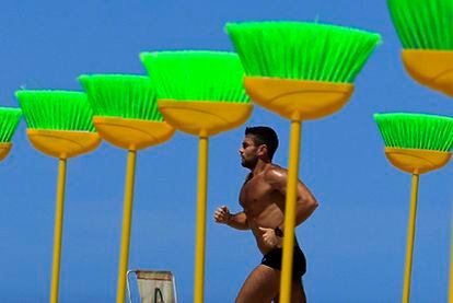 A man jogs past the brooms planted in the Copacabana beach on Monday.