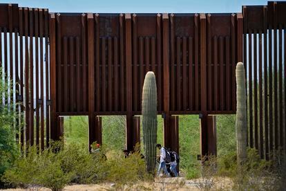 A group of migrants crosses through a gap in the wall in the middle of the desert between Sonora and Arizona, in August of this year.