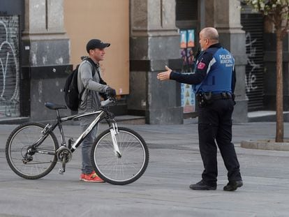 A Madrid local police officer tells a member of public that he cannot ride his bicycle under the state of alarm decreed in Spain on Saturday.