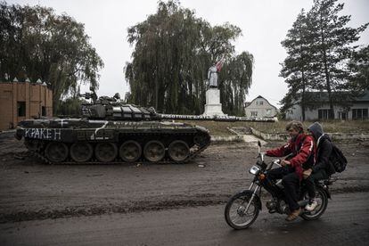 A motorcycle rider crosses a damaged tank in Izium.