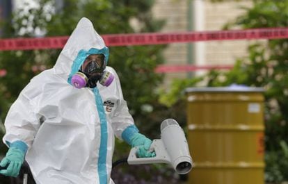 A hazmat worker cleans outside the apartment building of the infected hospital employee on Sunday.