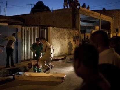 Workers place the body of a victim of Brazil's crime spree in a coffin