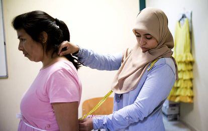 Loubna Day takes measurements from a colleague at the sewing workshop.