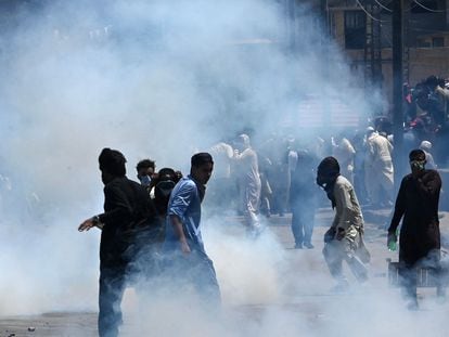Pakistan Tehreek-e-Insaf party activists and supporters of former prime minister Imran stand amid teargas fired by police during a protest against the arrest of their leader, in Peshawar on May 10, 2023.