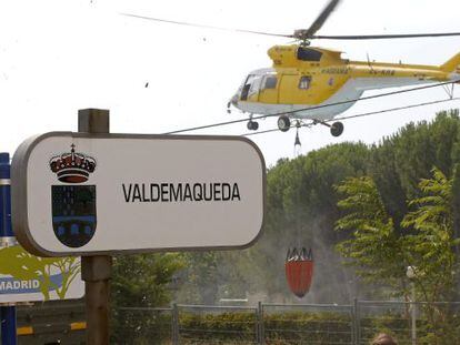 A helicopter collects water from a swimming pool to battle the blaze in Valdemaqueda, Madrid.
