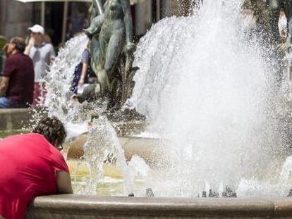 A woman cools down in a fountain in Valencia’s Plaza de la Virgen.
