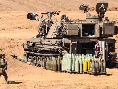 An Israeli soldiers walks past a M109-type self-propelled howitzer, upgraded version for IDF called 'Doher