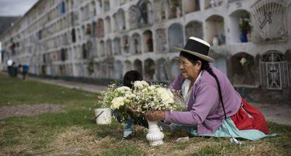 A woman lays flowers on the grave of a relative.