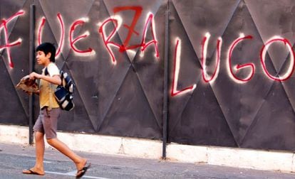 A boy passes in front of anti-Lugo graffiti with the words altered to read &quot;Power to Lugo.&quot;