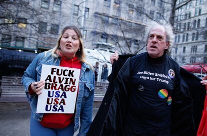 Supporters of Donald Trump carry banners insulting Manhattan D.A. Alvin Bragg and President Joe Biden outside the Manhattan Criminal Courts building on Monday.