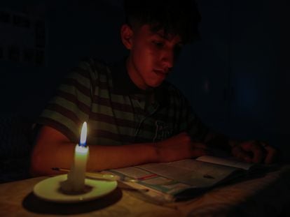 A student reads a text by candlelight in Quito, Ecuador, on April 17, 2024.